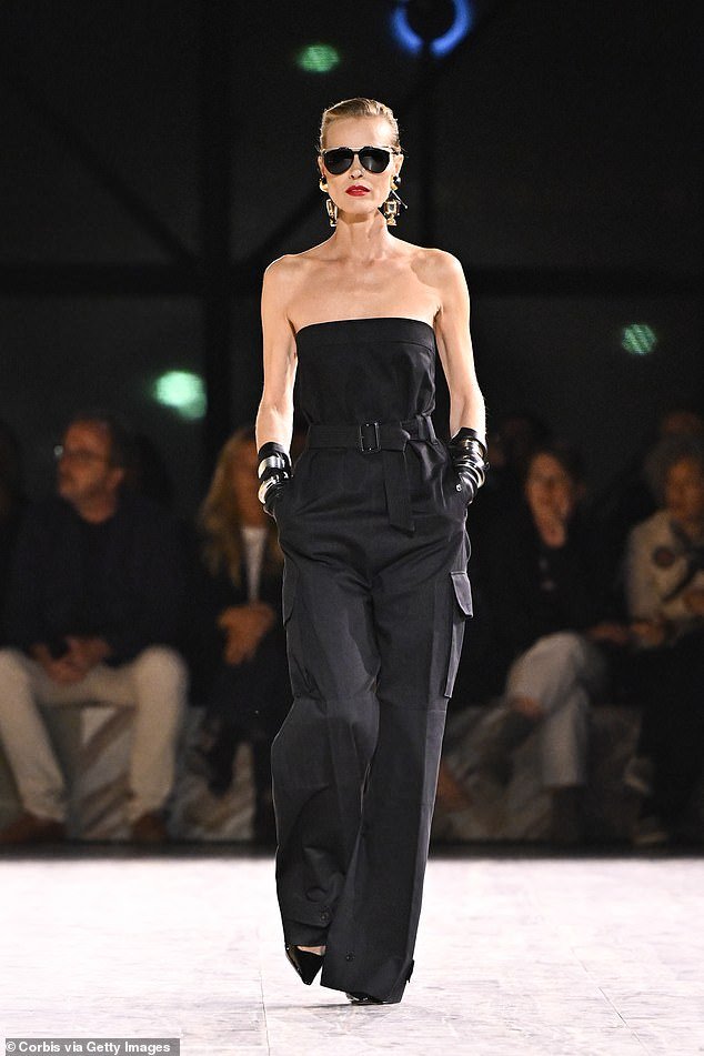 Supermodel Eva Herzigova, aged 50, amazes in an elegant black strapless jumpsuit and gloves while confidently striding down the Yves Saint Laurent runway during the Paris Fashion Week