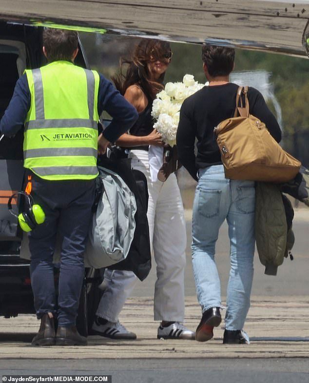 Pia Whitesell boards a private jet in Sydney, clutching a grand bouquet of white flowers following her 40th birthday celebration