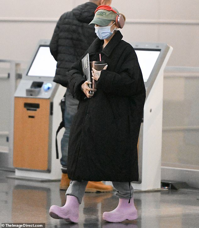 Ariana Grande Arrives at JFK Airport in New York Disguised in a Large Black Coat and Medical Mask, Making Her Almost Unrecognizable