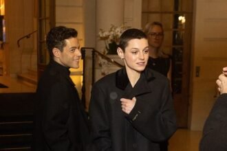 Emma Corrin and boyfriend Rami Malek bundle up in black coats as they leave The Ritz in Paris